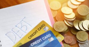 (debt written on paper with credit cards and coins spread around it)