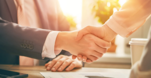 (Close-up of a professional handshake between two individuals in business attire, symbolizing agreement, trust, or a successful debt negotiation.)